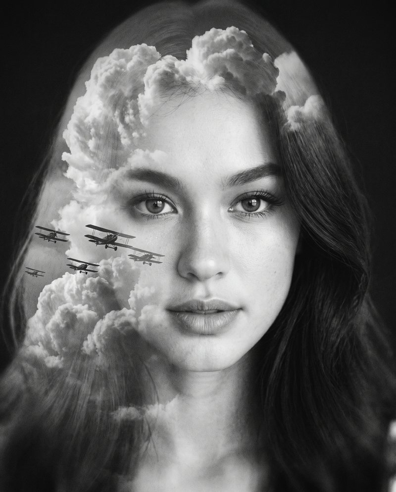 Nova Rai in a double exposure with clouds and little biplanes across her face, in black and white