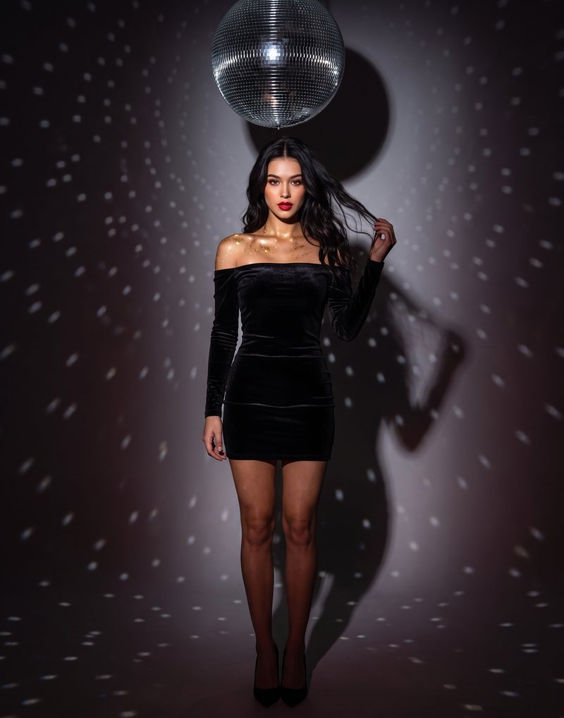 Nova Rai in black velvet under a mirror ball, scattered light on the wall