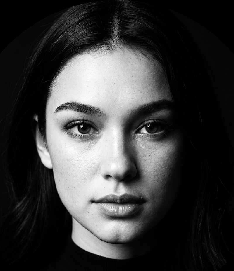 Nova Rai in a black and white portrait under one hard light, half her face in shadow